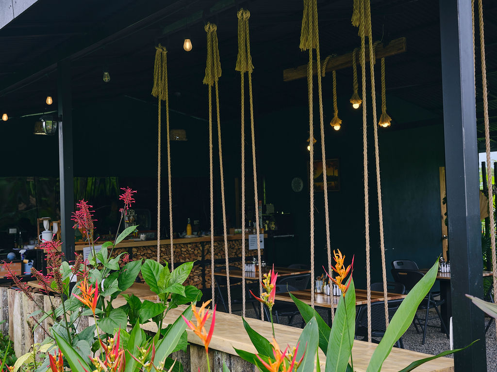 Swing seats at the restaurant bar among heliconias