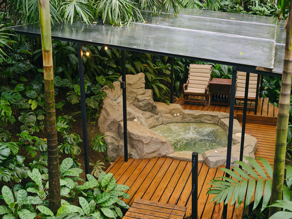 Covered deck with a rock-edged jacuzzi seen from the garden