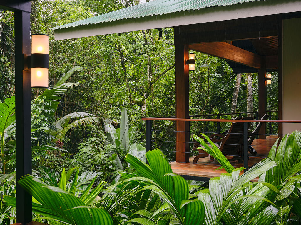 Exterior of the Bungalow Deluxe King Waterfall among the trees, porch lamps lit