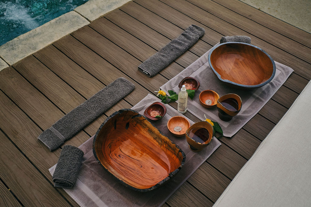 Wooden bowls and fresh flowers laid out for a spa ritual