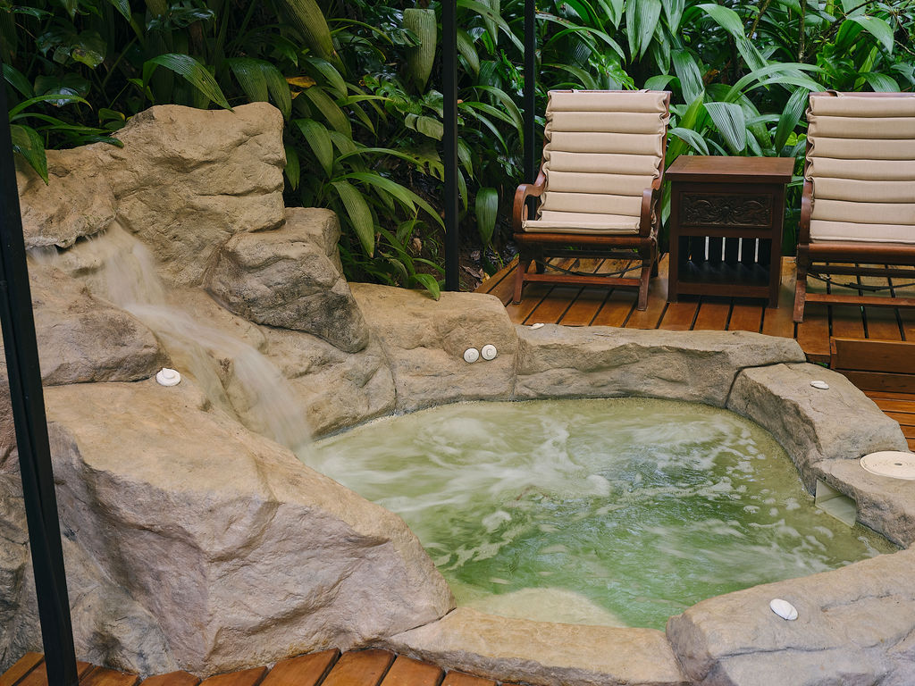 Rock-edged jacuzzi with sun loungers on a wooden deck