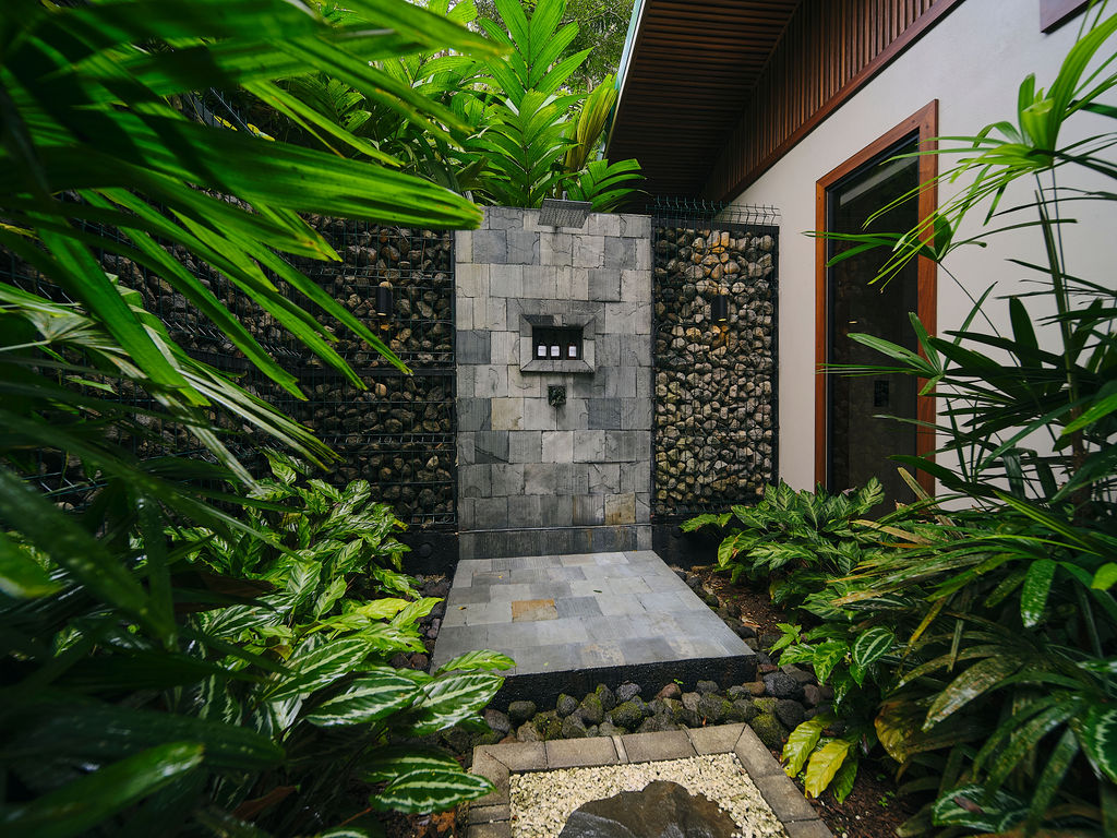 Outdoor stone shower of the Bungalow Deluxe King Waterfall open to the forest