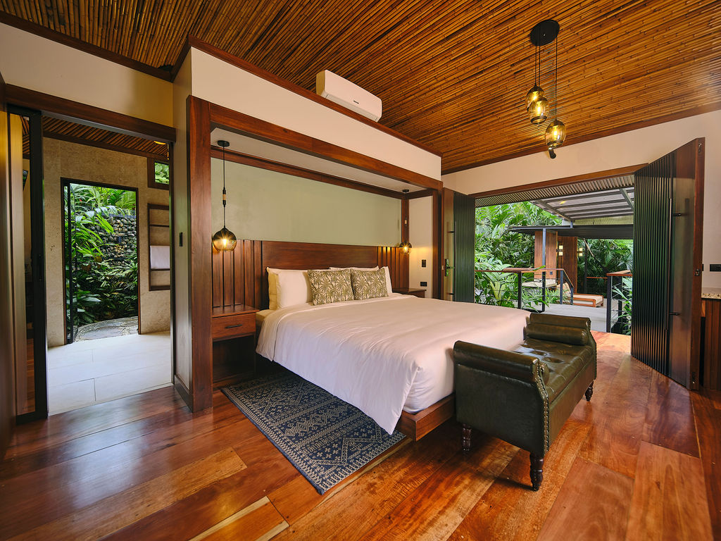 King bed of the Bungalow Deluxe King Waterfall with the doors open to the garden shower