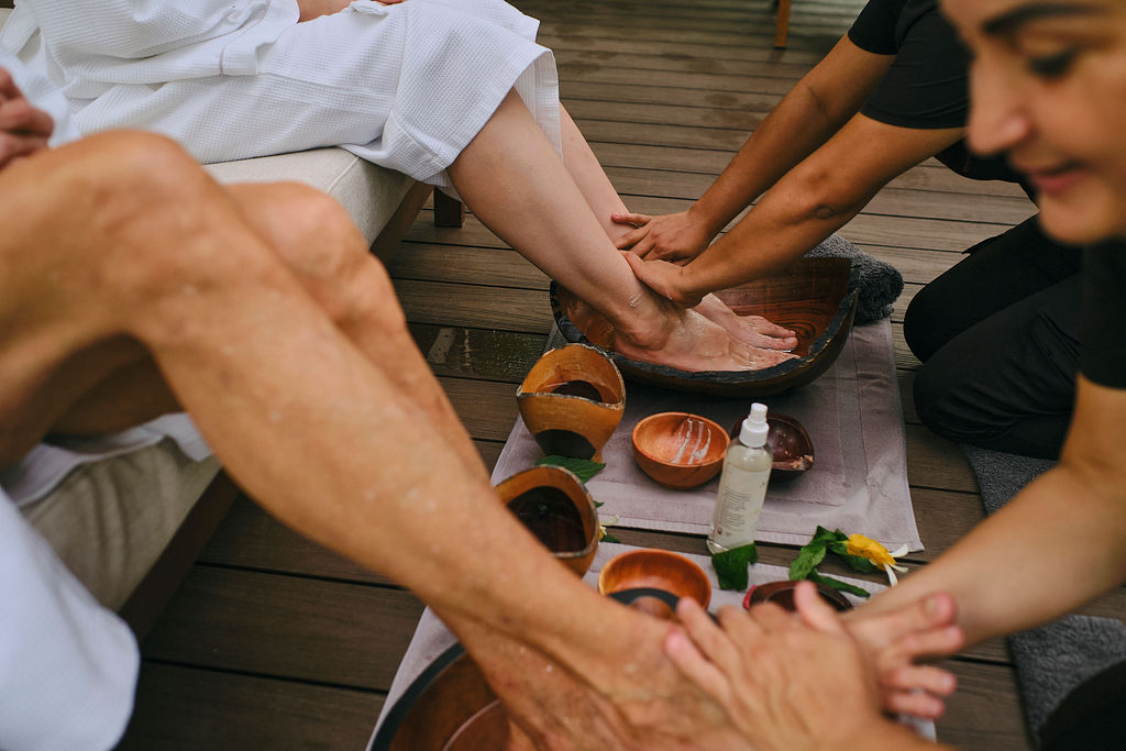 Therapists giving a foot ritual to two guests on the deck