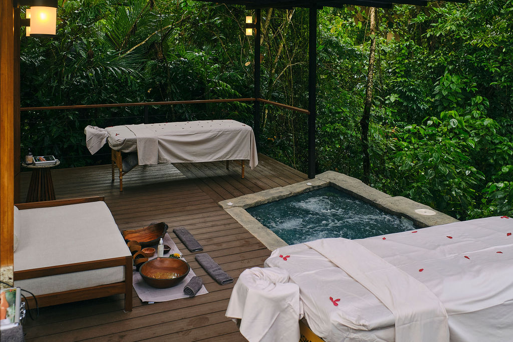 Massage table set beside a private jacuzzi on a forest deck