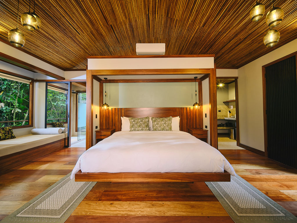 Platform king bed under a wooden canopy frame in the Bungalow Luxury King
