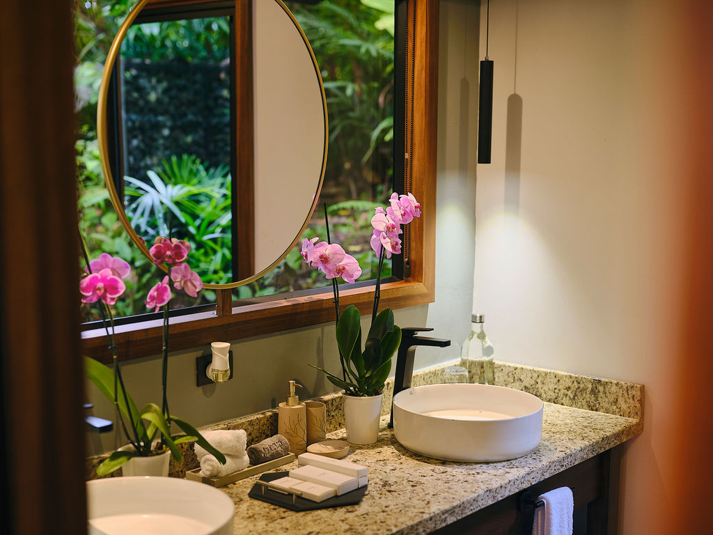 Bathroom vanity with a round mirror and fresh orchids